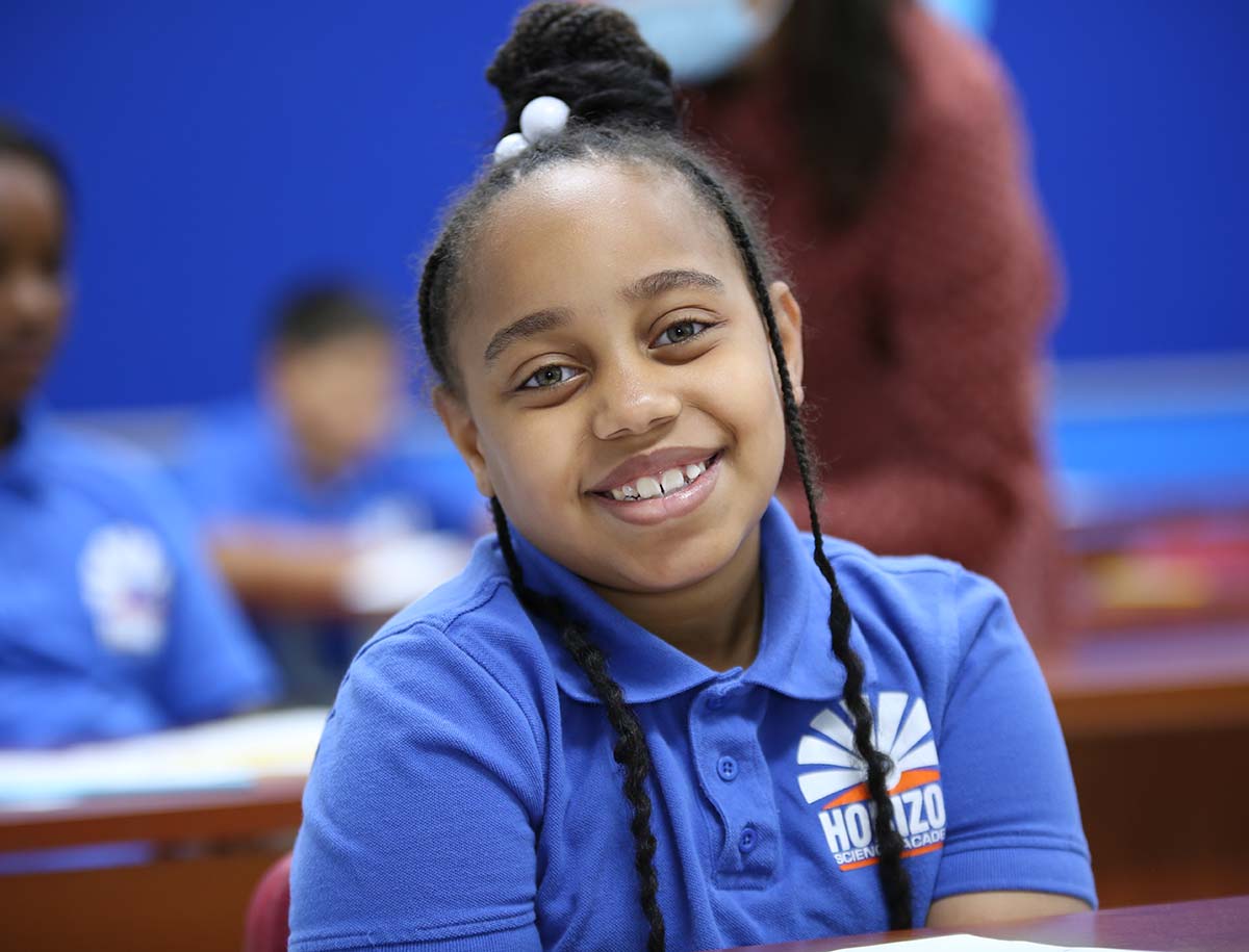 Elementary student smiling and posing together in a classroom.